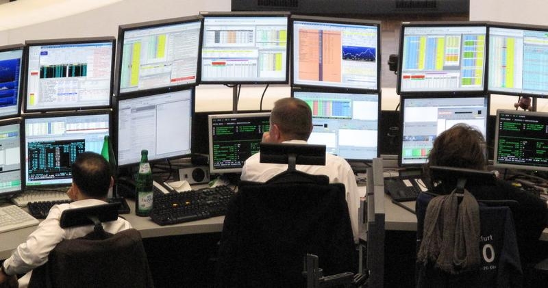 Traders are pictured at their desks at the trading room near by the DAX board at the Frankfurt stock exchange